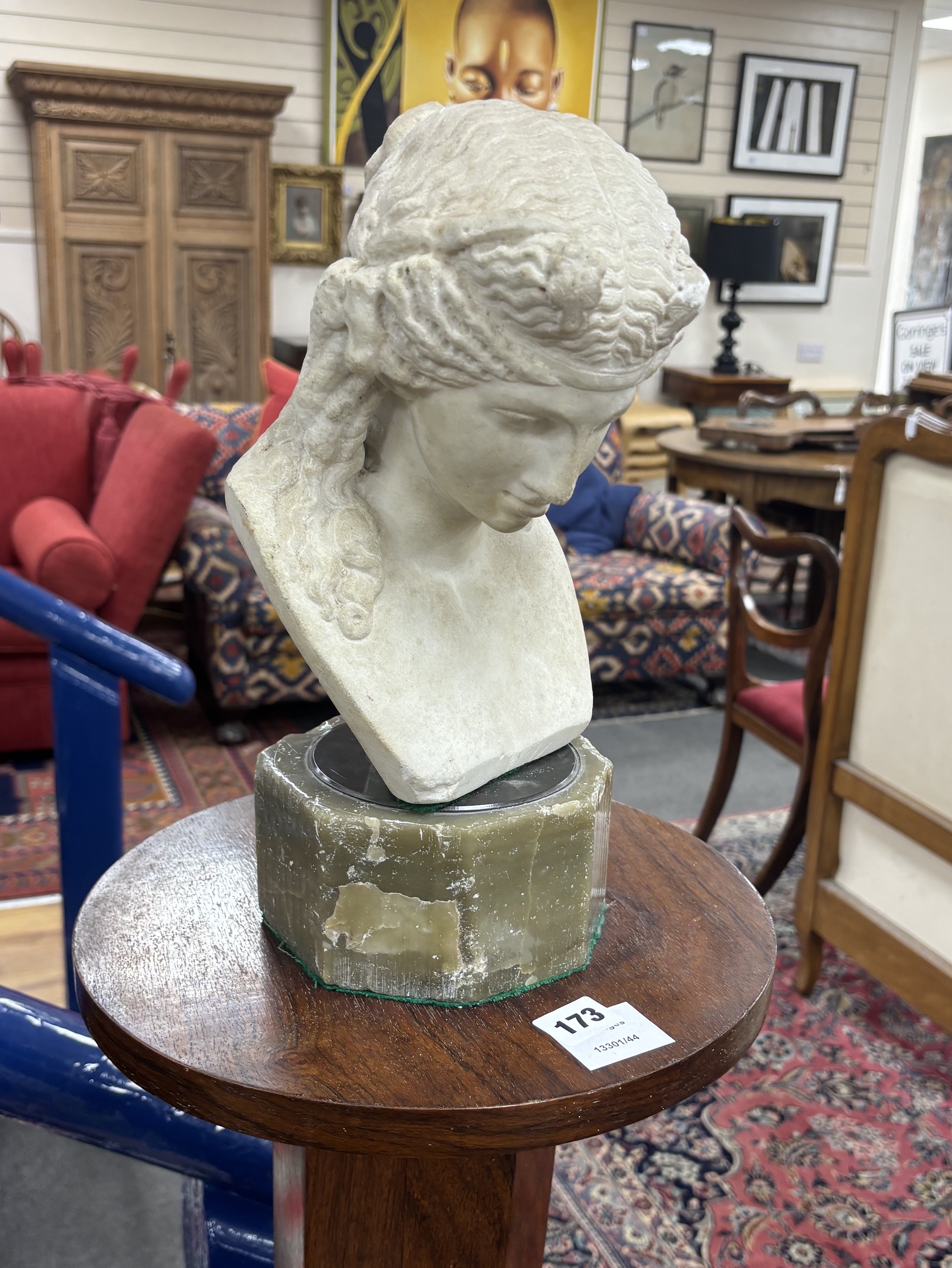 After the Antique, a carved marble bust of a young woman on octagonal onyx plinth and rosewood pedestal, combined height 142cm